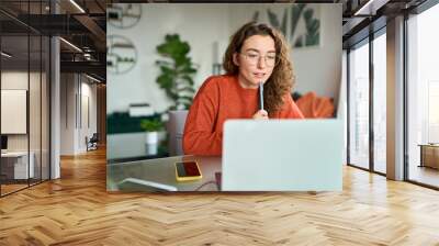 Young girl female student using laptop elearning or remote working at home office looking at computer watching webinar, learning training, studying online seminar or video calling for work meeting. Wall mural