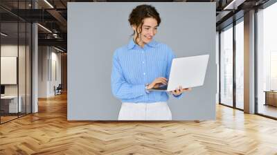 Young happy business woman professional executive hr manager using laptop advertising web service, holding computer searching job online, elearning standing isolated on gray background, studio shot. Wall mural