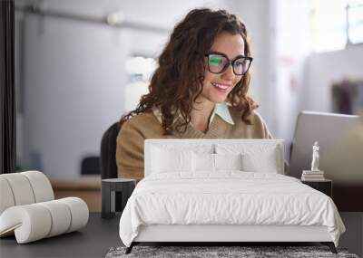 Young happy professional business woman worker employee sitting at desk working on laptop in corporate office. Smiling female student using computer technology learning online, doing web research. Wall mural