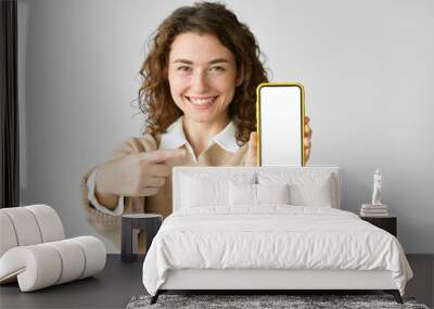 Young happy woman model pointing at big mobile phone screen presenting new trendy app at cell, showing blank empty display cellphone template, holding smartphone mock up isolated on white background. Wall mural