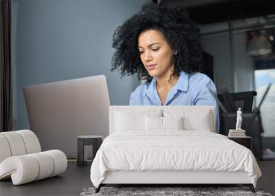 Young serious African American female ceo lawyer businesswoman sitting at desk working typing on laptop computer in contemporary corporation office. Business technologies concept. Wall mural