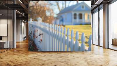 A charming white picket fence surrounds a quaint blue house, captured in soft sunlight, embodying a peaceful suburban vibe. Wall mural