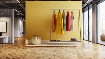 Sleek, modern clothes rack with vibrant outfits in a minimalist dressing area. Stylish decor and neutral tones create a fashion-forward space. Wall mural