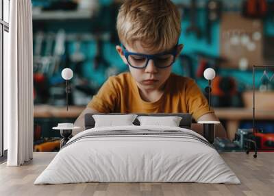 A young boy with glasses intently focused on repairing or fixing various household items and gadgets on a workbench surrounded by an array of tools and equipment in a cozy Wall mural