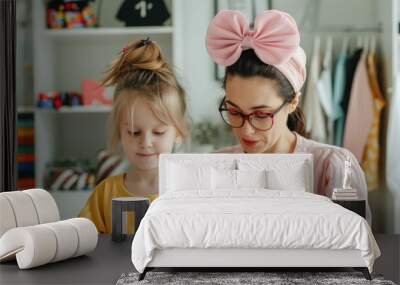 Cheerful young mother and her adorable daughter having fun playing dress up with costumes and accessories in their home  The two females are bonding smiling Wall mural