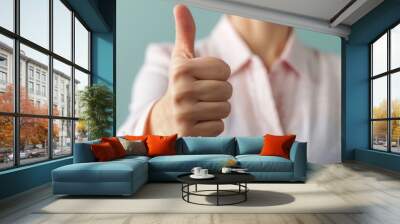 Close up photograph of a hand making a thumbs up gesture conveying a sense of customer satisfaction positive feedback and approval  The image represents the concept of successful client service Wall mural