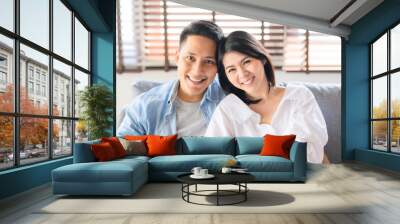 Asian couple in love smiling relaxing on sofa at home Wall mural