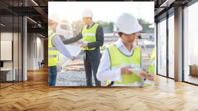 Engineer and builder review blueprint during team meeting at construction site in the morning with sunlight Wall mural