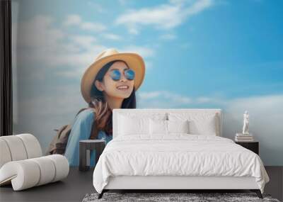 Beautiful Happy young Asian tourist woman wearing a beach hat, sunglasses, and backpacks going to travel on holidays on a blue sky background. travel concept. Wall mural