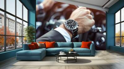 Close-up top view of a businessman wearing an expensive watch in a black suit keeping hand on the steering wheel while driving a luxury car. Wall mural