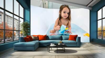 Happy toddler girl playing with toys in bathtub  Wall mural