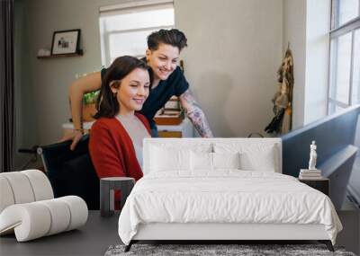 Lesbian woman showing her wife something on computer in home office Wall mural