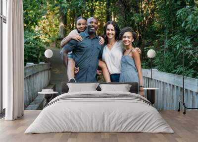 Portrait of happy mixed race family on bridge in nature park Wall mural