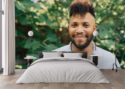 Portrait of smiling, happy confident black man with mohawk standing outdoors in garden Wall mural