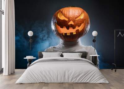 A pumpkin or Jack-o-lantern head with a mummy body with a spooky and dark background; happy halloween and fall season festivity; horror and scary; a spooky pumpkin head mummy with glowing eyes Wall mural