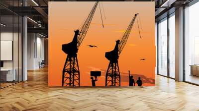 Silhouette of harbour workers and port cranes at sunset sky Wall mural