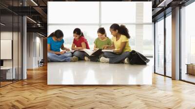 Preteen girls sitting on floor with schoolwork. Wall mural