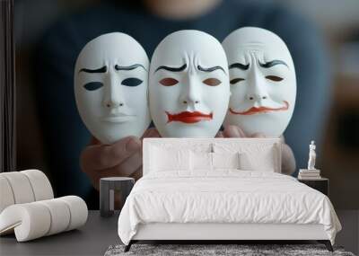 A person presents three masks, each expressing a distinct emotion, reflecting the complexity of human feelings. Wall mural