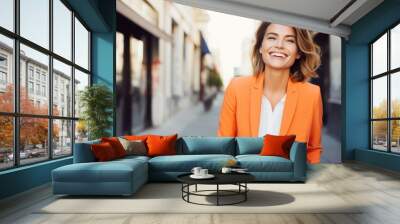 A stylishly dressed woman in a vibrant orange suit beams a radiant smile on a city street, capturing the essence of confident urban fashion. Wall mural