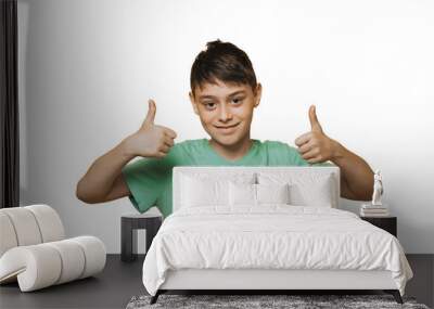 Portrait of attractive young school boy dressed in a green t-shirt, cute smiling showing thumbs up over transparent background, isolated. Copy space. Success people emotions. Wall mural