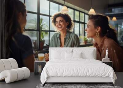 Three friends share a joyful moment, laughing together over brunch at a cozy, sunlit café with large windows and green plants. Wall mural