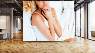 young pretty blond woman in bed covered white sheets smiling che Wall mural