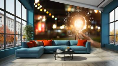 hand holding light bulb in front of global, show the world's consumption with icons energy sources f Wall mural