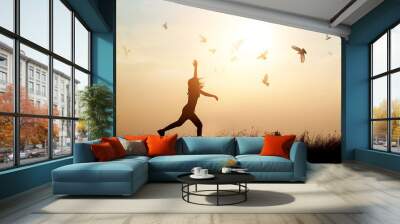 Woman and flying birds enjoying life in nature on sunset background Wall mural