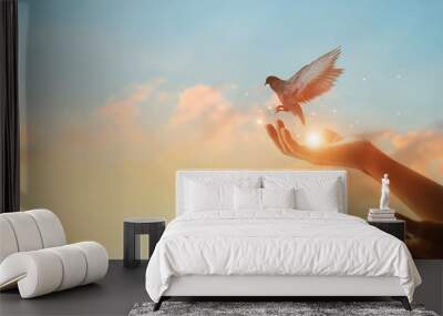 Woman praying and free bird enjoying nature on sunset background, hope concept Wall mural