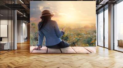 Woman relaxing with smartphone in hand on outdoors in sunset rural nature background Wall mural