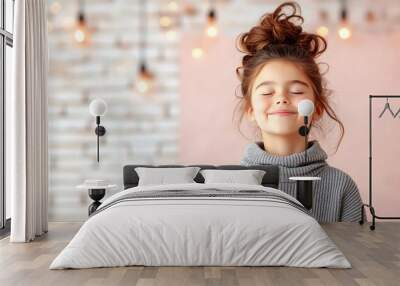 Happy Little Girl with Eyes Closed and hair bun Smiling Face wearing grey sweater ,blurry backgroud and beautiful bokeh Wall mural