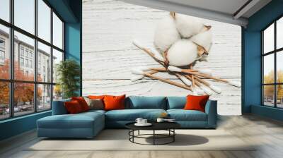 Cosmetic eco sticks on a cardboard base are scattered with cotton on a white background. Wall mural