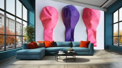 Two pink and one purple balloon. Deflated balloons are lying on the table. Toys for children. Background, space for text. Wall mural