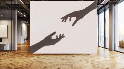 Grey shadows of hands reaching each other on the wall. Abstract blurred effect. Wall mural