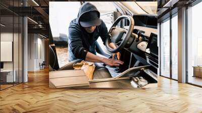 At the car wash, a latin man is vacuuming a sleek and modern car. Wall mural