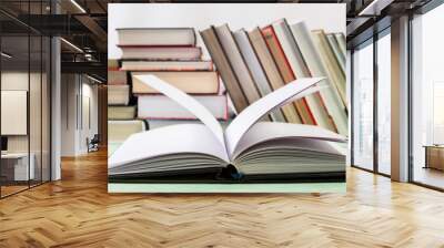 Open book and pile of various books on wooden background. With copy space for your text Wall mural