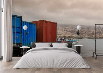 Colorful harbor in Funchal, Madeira. Cityscape with boats on the water, containers in the dock, houses on the hills under the cloudy sky on a rainy foggy day Wall mural