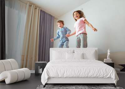 Children jump on the bed.The boy and the girl are having fun at home Wall mural