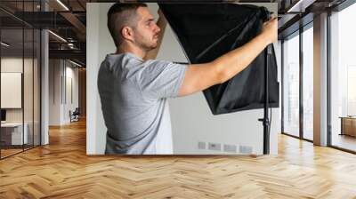 Photo of a young and attractive photographer preparing the photography set of lights  Wall mural