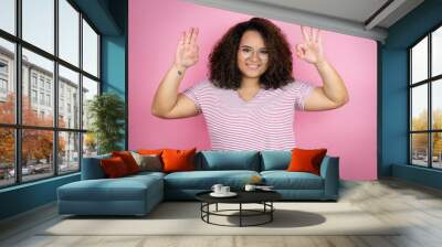 Young african american woman wearing red stripes t-shirt over pink background doing ok sign with fingers and smiling, excellent symbol Wall mural