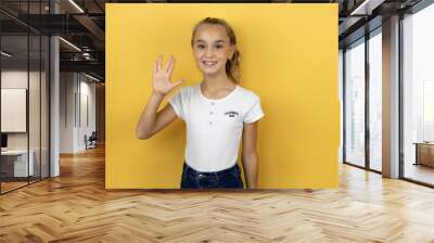 Young beautiful child girl standing over isolated yellow background doing star trek freak symbol Wall mural