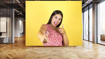 Young beautiful woman over isolated yellow background pointing to you and the camera with fingers, smiling positive and cheerful Wall mural