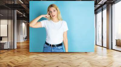 Young beautiful woman wearing casual t-shirt over isolated blue background smiling and thinking with her fingers on her head that she has an idea. Wall mural