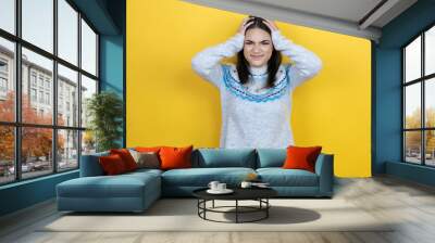 Young caucasian woman wearing casual sweater over yellow background suffering from headache desperate and stressed because pain and migraine with her hands on head Wall mural