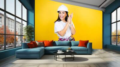 Young caucasian woman wearing hardhat and builder clothes over isolated yellow background clapping and applauding happy and joyful, smiling proud hands together Wall mural