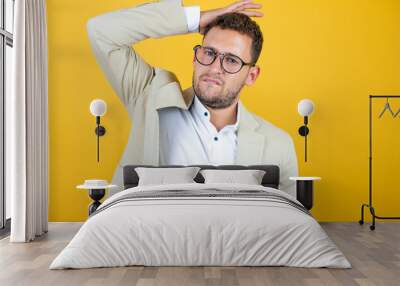 Young handsome businessman wearing suit over isolated yellow background putting one hand on her head smiling like she had forgotten something Wall mural