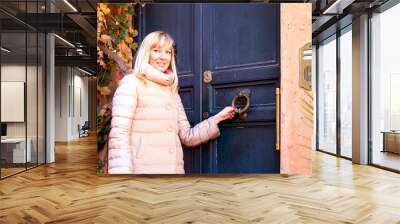 Young woman standing at the door of an old house on a sunny autumn day. Wall mural