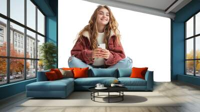 Happy young girl sitting on the floor, holding smartphone in hands and looking away, on isolated transparent background Wall mural