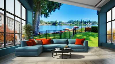 Backyard area with well kept lawn and metal fence. Beautiful water view Wall mural