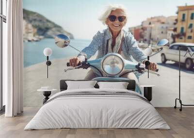 Cheerful senior woman riding blue scooter in Italy, retired granny enjoying summer vacation, trendy bike road trip Wall mural